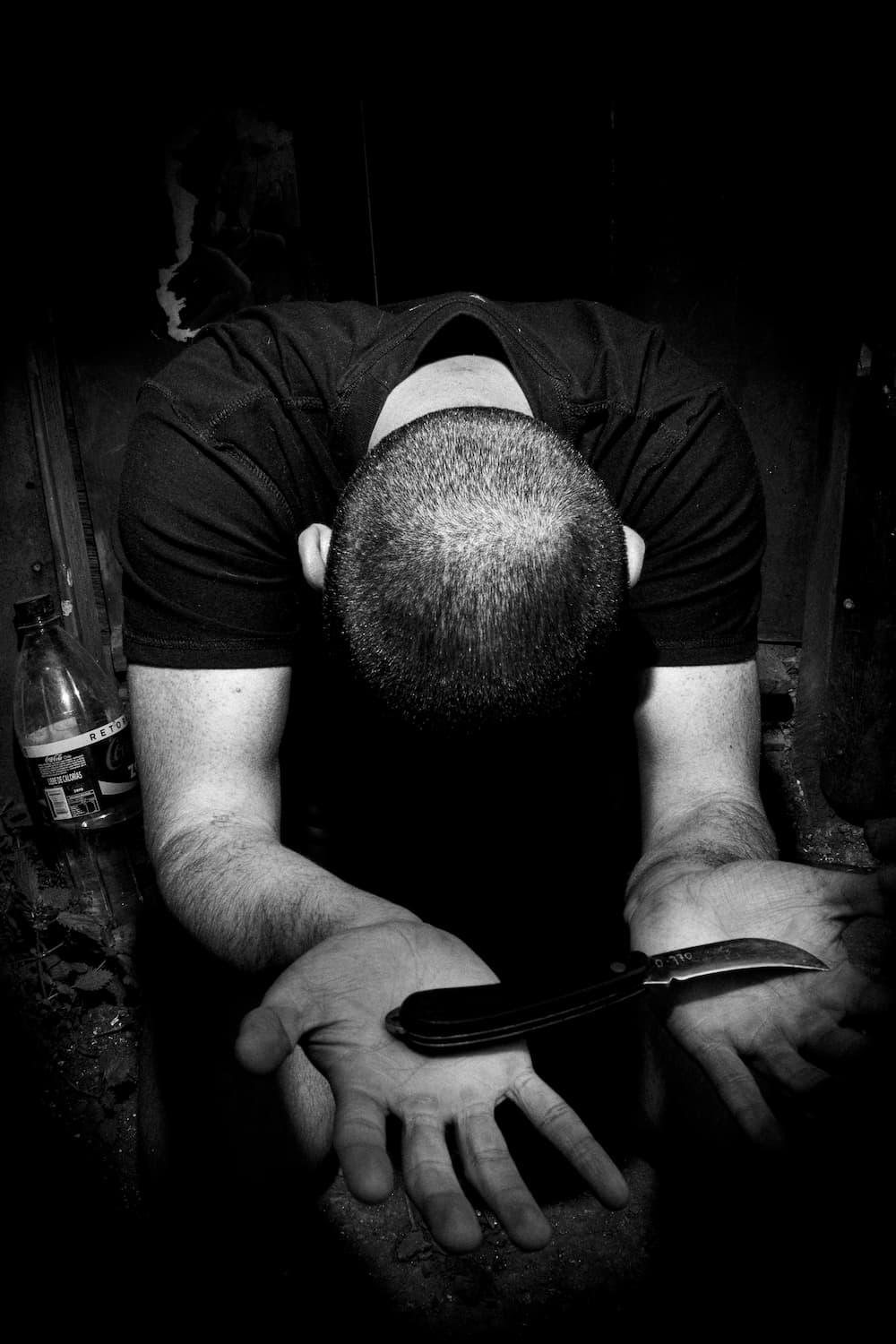 Fotografia del padre del artista de rodillas entregando una navaja