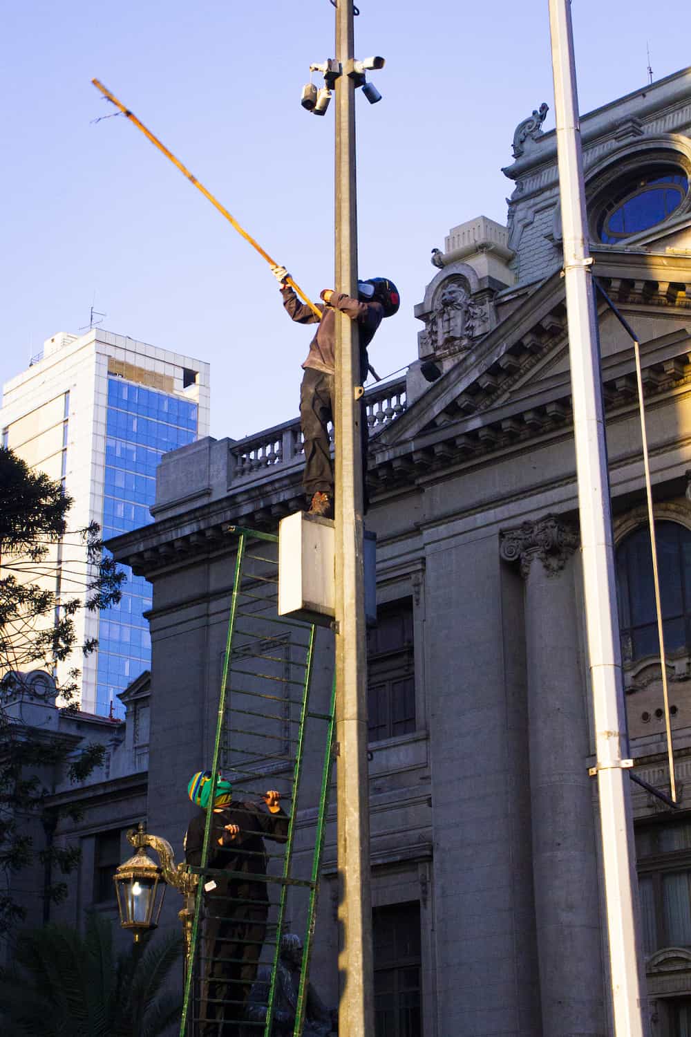 Fotografia de dos jovenes golpeando una camara de seguridad con un palo