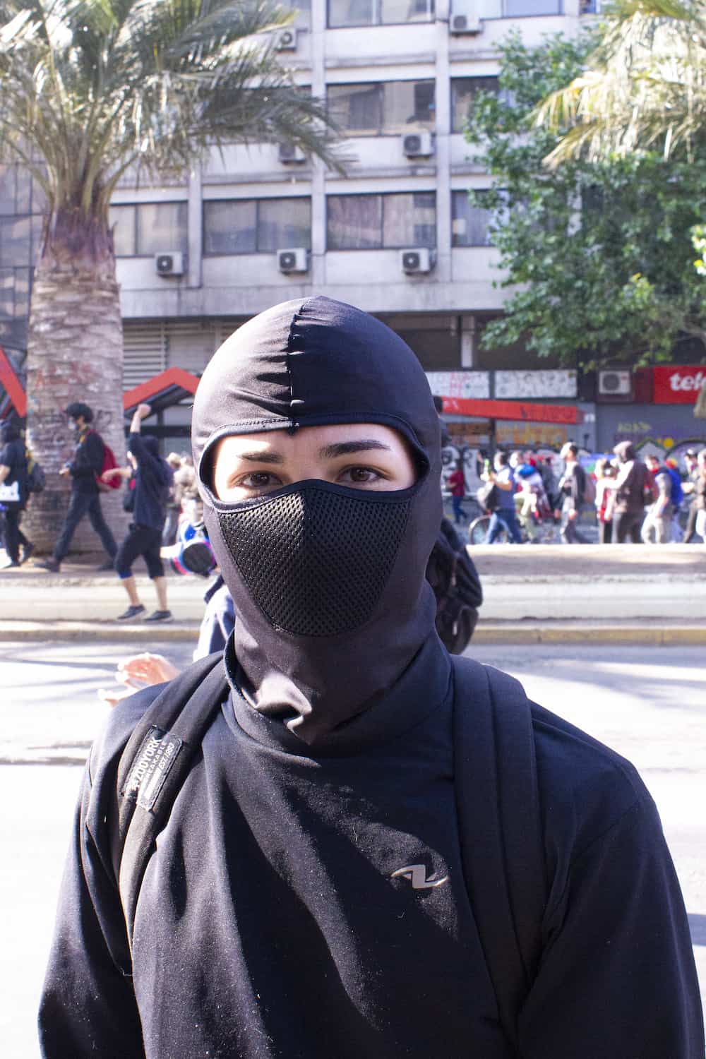 Fotografia de un joven con la cara tapada mirando a la camara