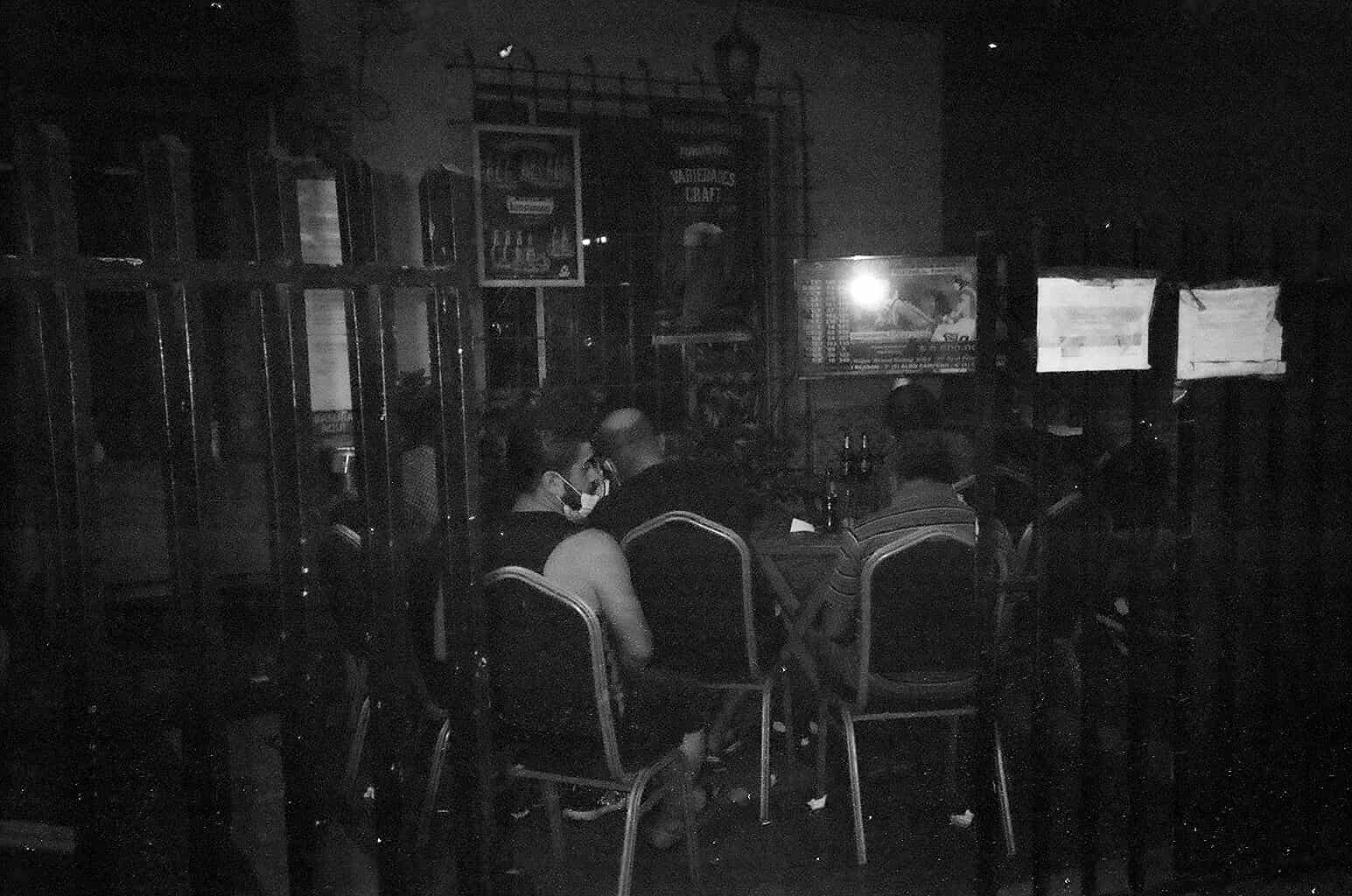 Fotografia  de un grupo de personas sentadas en un bar frente una TV
