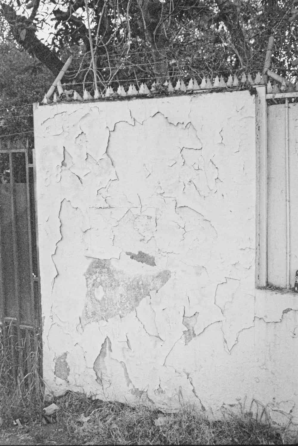Fotografia de una pared con alambre de puas y en deterioro