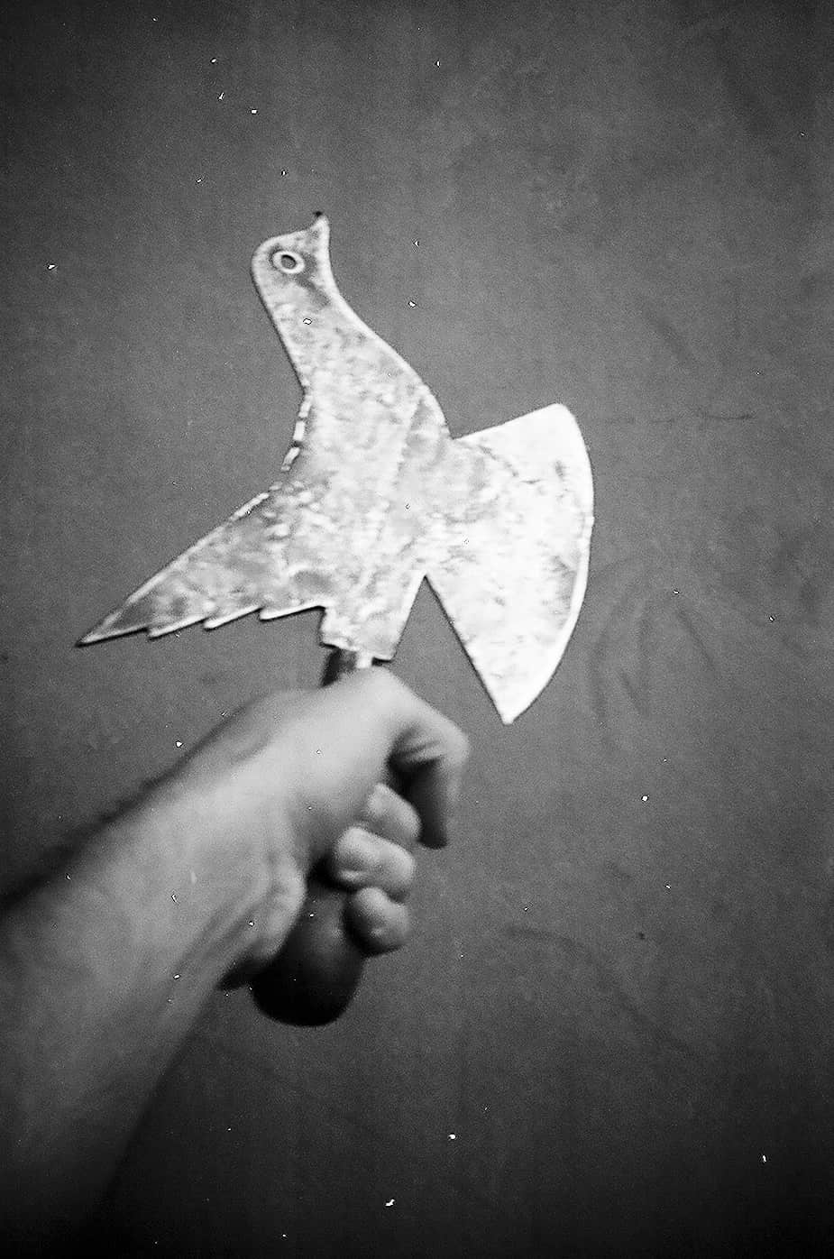 Fotografia de una mano soteniendo un utencilio con forma de pajaro