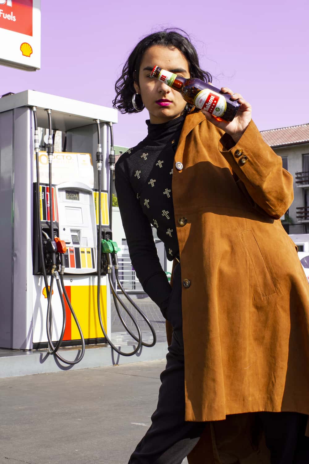 Fotografia de una joven en una estacion de servicio soteniendo una cerveza